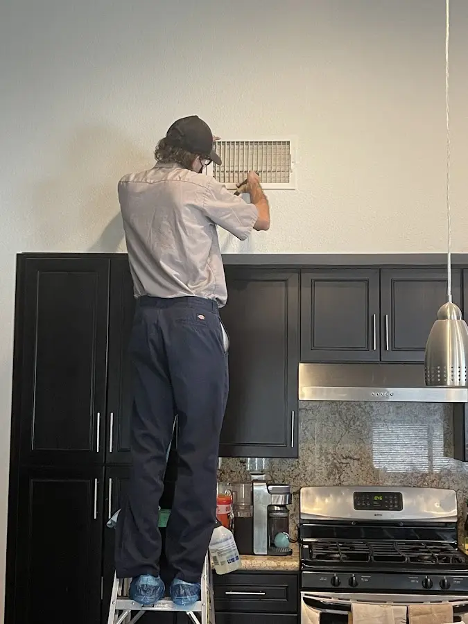 Technician inspecting an air vent during HVAC service in Anniston